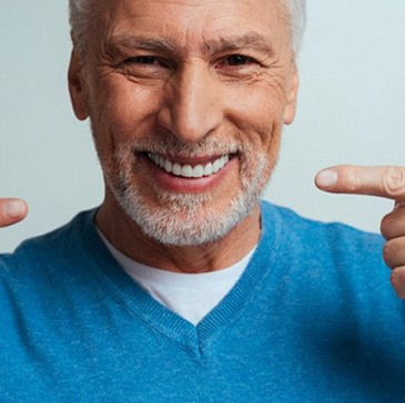a man pointing at his dentures and new smile