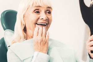 a patient checking her dentures with a mirror