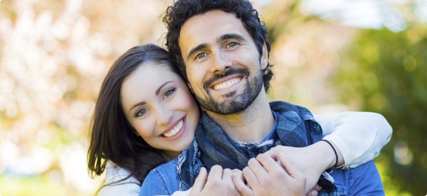 Smiling man and woman hugging outdoors with dental implants in Waco