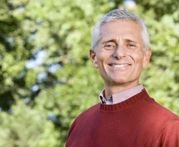 Man in red sweater smiling outdoors