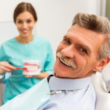 Senior man in dental chair smiling during dental implant consultation