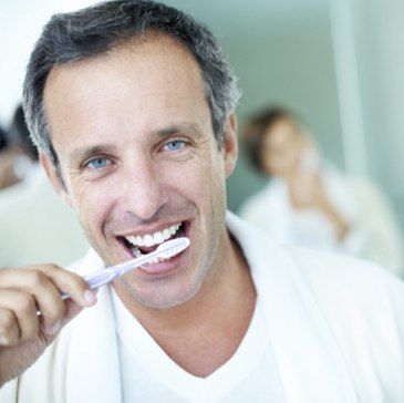 Man smiling while brushing teeth