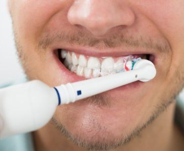 Close up of man using electric toothbrush