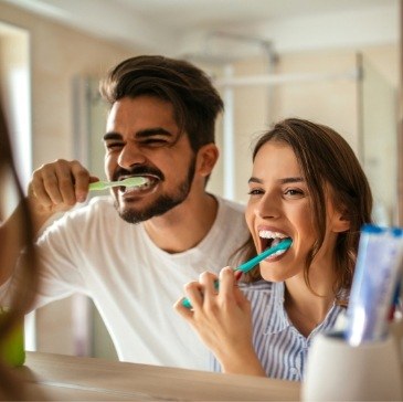 Man and woman brushing their teeth together