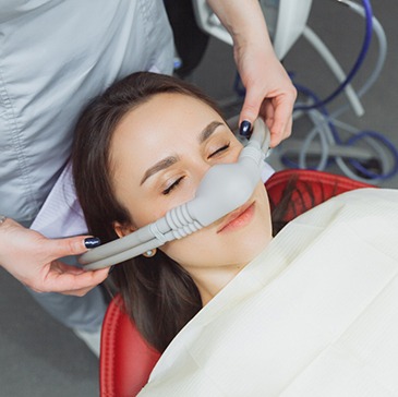 Dental assistant placing nasal piece over patient's nose