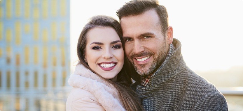 Man and woman outdoors in coats smiling with Teeth in a Day in Waco