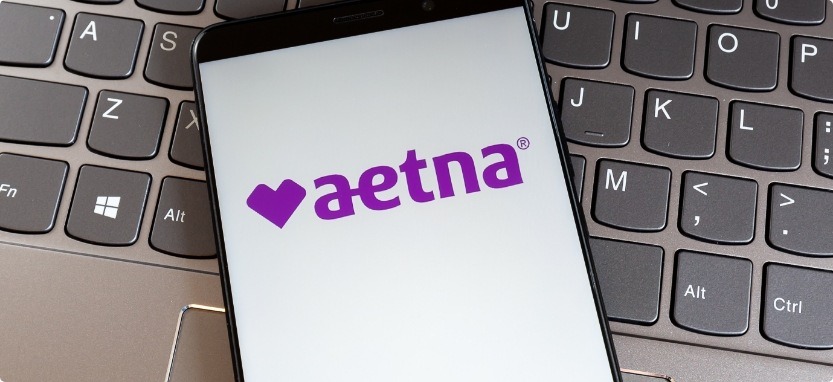 Phone showing Aetna dental insurance logo resting on laptop keyboard