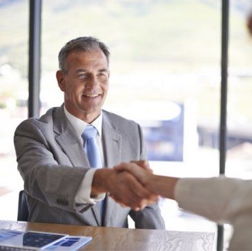 Man in suit shaking hands with someone out of frame