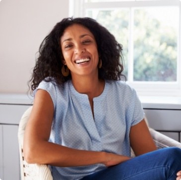 Smiling woman in light blue blouse sitting in armchair