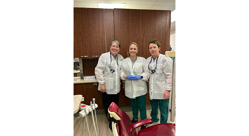 Three dental team members smiling in dental treatment room