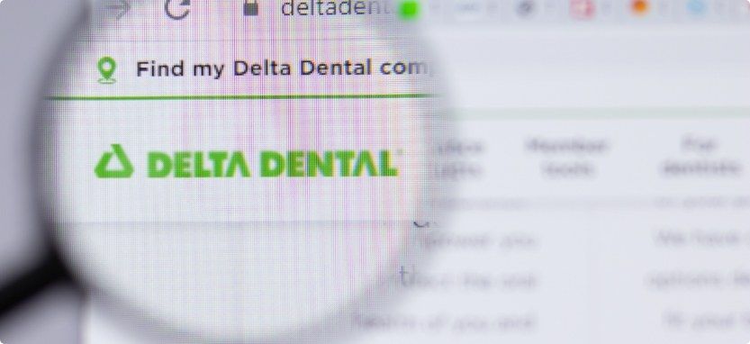 Magnifying glass in front of computer screen show Delta Dental insurance website
