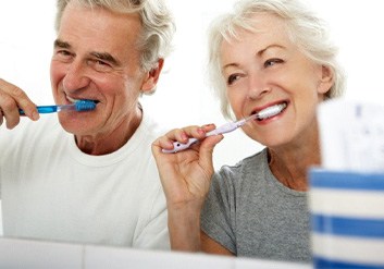 a mature couple brushing their teeth together