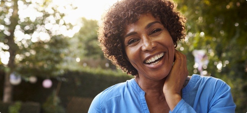 Woman in blue blouse grinning outdoors with dental crowns in Waco