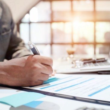 Person filling out dental insurance form on clipboard