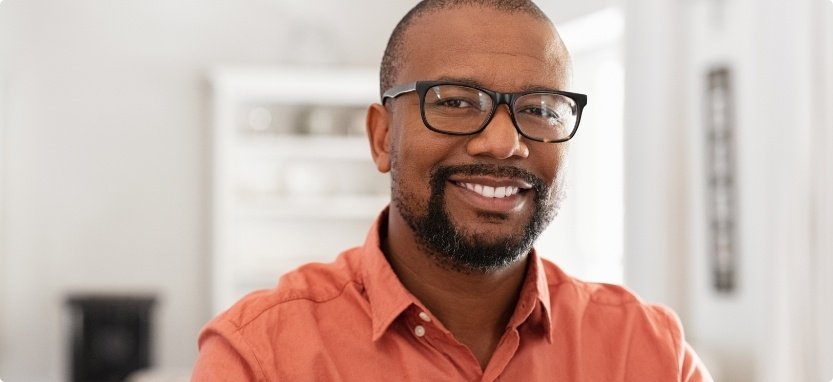 Man in orange shirt smiling with dentures in Waco