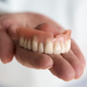 Dentist holding a full denture in their hand