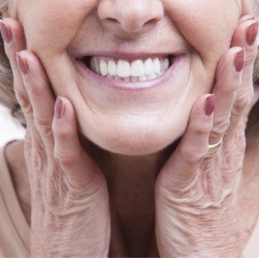 Close up of smiling senior woman holding her cheeks