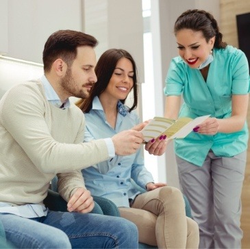 Dental team member showing a pamphlet to two dental patients