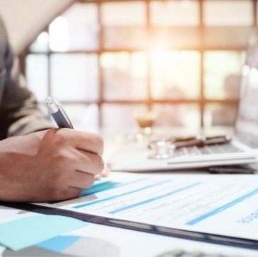 Person filling out form on clipboard