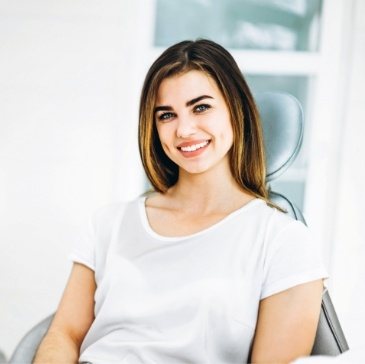 Young woman in white T shirt smiling in dental chair