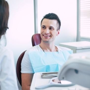 Man in dental chair talking to dental team member