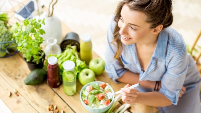 Smiling young woman eating salad