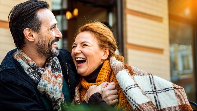Man and woman laughing outdoors and wearing coats and scarves