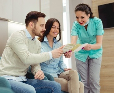 Dental team member showing a pamphlet to two patients