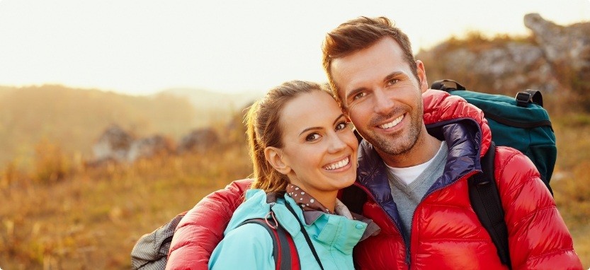 Man and woman on hike smiling with metal free dental restorations in Waco