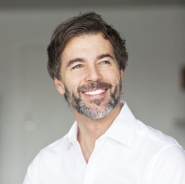 Older man in white collared shirt smiling