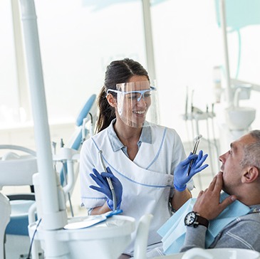 Dentist smiling while talking to patient in treatment chair