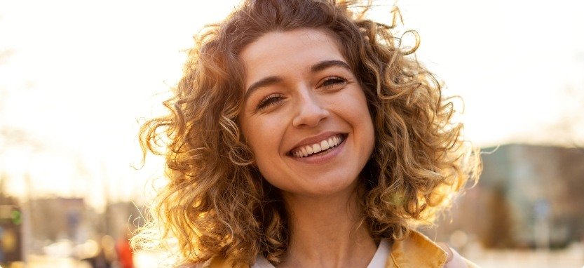 Woman with curly hair smiling after dental services in Waco