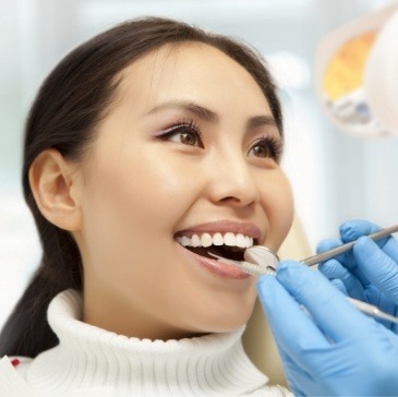 Woman in white sweater smiling during dental checkup