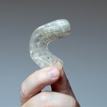 Hand holding a clear nightguard for bruxism