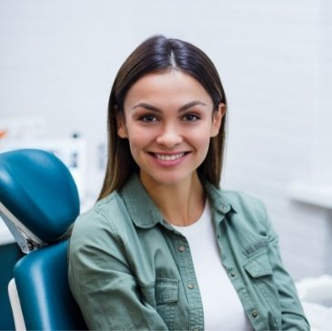 Young woman in green shirt smiling in dental chair