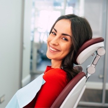 Woman in red shirt smiling in dental chair