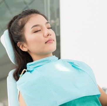 Relaxed woman in dental chair with eyes closed thanks to sedation dentistry