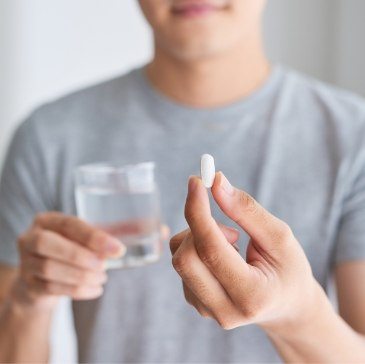 Person holding pill and glass of water