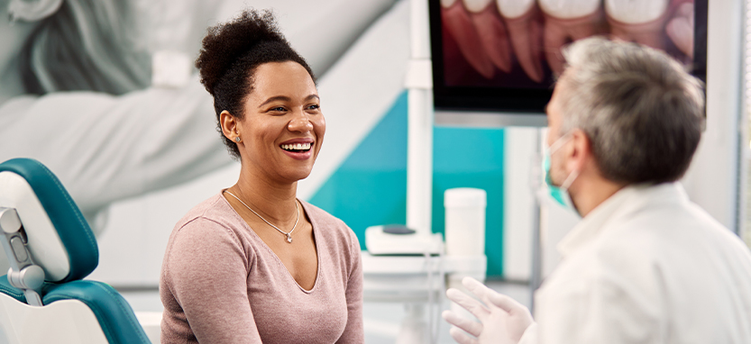 Young woman in dental chair laughing with Waco dentist