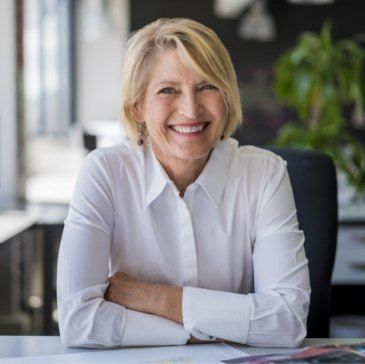 Smiling woman in white collared shirt sitting at desk