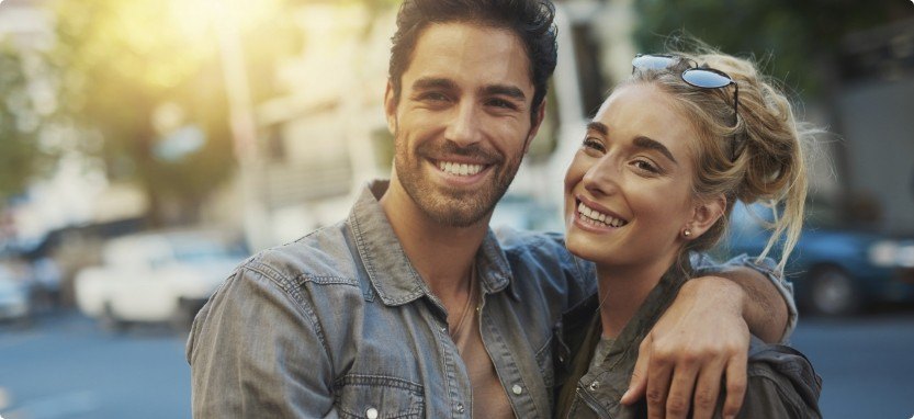 Man and woman smiling on city street with tooth colored fillings in Waco