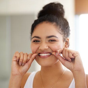 Young woman smiling while flossing her teeth