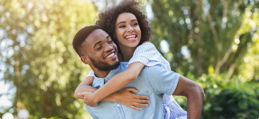 Man giving woman piggyback ride after tooth extractions in Waco