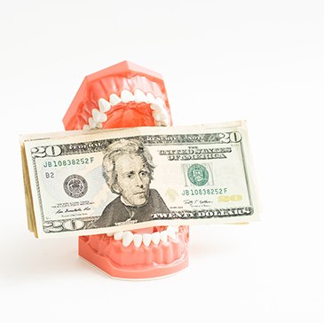 A plastic model of teeth holding money