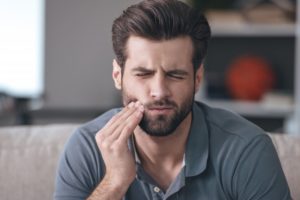 pained man at home wondering if he has an urgent dental emergency