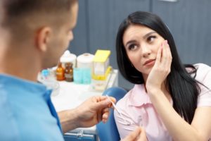 A patient holding her mouth while listening to her dentist.