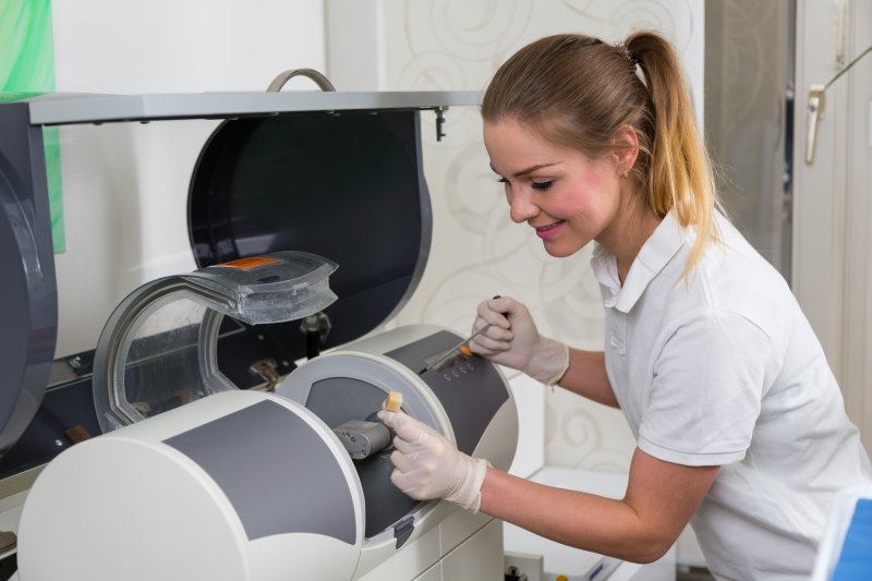 A dental assistant operating a CEREC milling machine