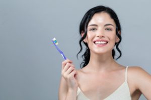 Smiling, healthy woman holding a clean blue toothbrush