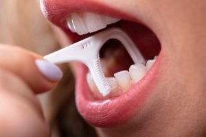 a person using a flossing tool to remove something between their teeth