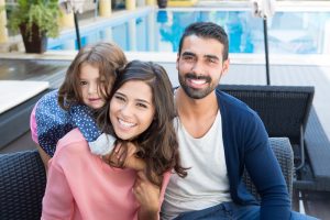 young family smiling beside a pool